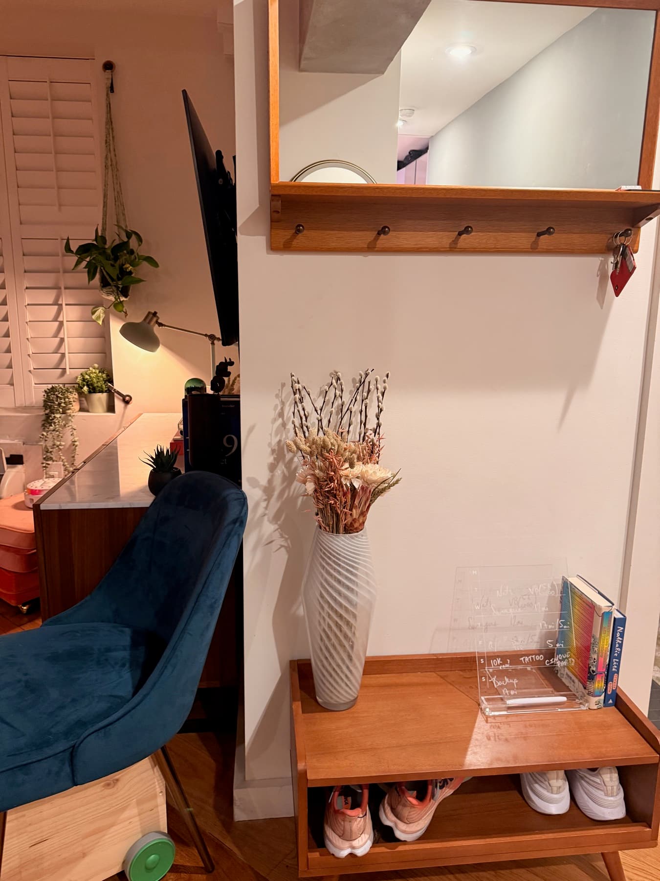 The entryway: dried flowers, blue velvet chair, running shoes by the door