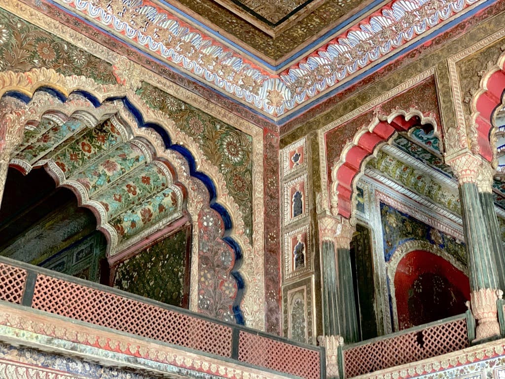 Polylobed arches framed in floral fresco and gilt