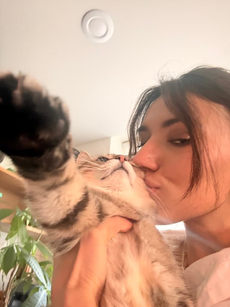 Jenn kissing Xiao while Xiao reaches one paw toward the camera.